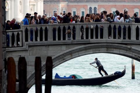 Tourists walk on a bridge as a gondolier rows his gondola near St.Marks Square in Venice, Italy, April 2, 2019. PHOTO BY REUTERS/Guglielmo Mangiapane