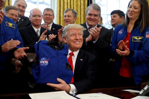 U.S. President Donald Trump receives a NASA jacket during a signing ceremony for S442, the NASA transition authorization act, in the Oval Office of the White House in Washington, U.S., March 21, 2017. PHOTO BY REUTERS/Kevin Lamarque