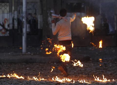 A supporter of the army and police throws back a Molotov cocktail at students of Al-Azhar University who are supporters of the Muslim Brotherhood and ousted Egyptian President Mohamed Mursi, during clashes outside the Al-Azhar University