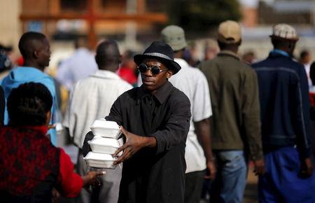 A volunteer hands out food to foreign nationals who fled anti-immigrant violence, at a temporal refuge camp in Primrose, outside Johannesburg, April 18, 2015. PHOTO BY REUTERS/Siphiwe Sibeko