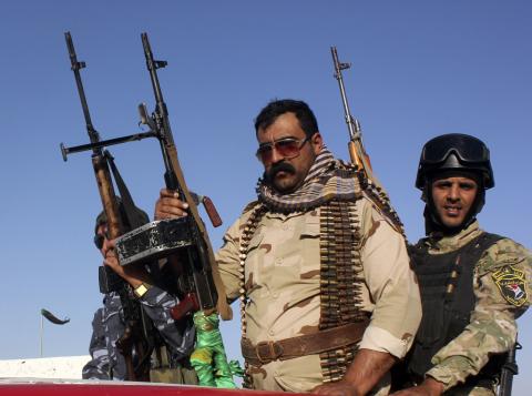 Shi'ite volunteers, who have joined the Iraqi army to fight against the predominantly Sunni militants from the radical Islamic State of Iraq and the Levant (ISIL), hold their weapons during a parade down a street in Kanaan, Diyala province