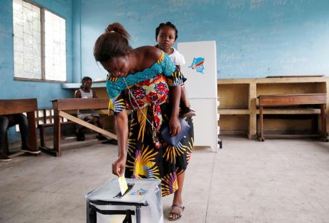 A woman carries her baby as she casts her vote at a polling station during the presidential election in Kinshasa, Democratic Republic of Congo, December 30, 2018. PHOTO BY REUTERS/Baz Ratner