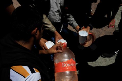 Central American migrants returned from the U.S. to Mexico under the Migrant Protection Protocols (MPP), drink water in Tijuana, Mexico, July 18, 2019. PHOTO BY REUTERS/Carlos Jasso