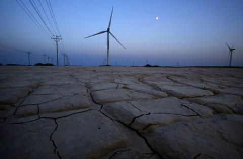 Cracked earth marks a dried-up area near a wind turbine used to generate electricity at a wind farm in Guazhou, 950km (590 miles) northwest of Lanzhou, Gansu Province September 15, 2013. PHOTO BY REUTERS/Carlos Barria