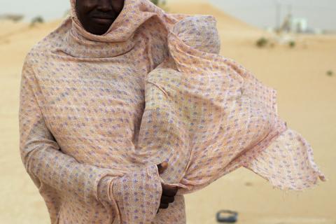 A woman shields her child from the wind while walking on sand dunes in Nouakchottt, June 22, 2014. PHOTO BY REUTERS/Joe Penney