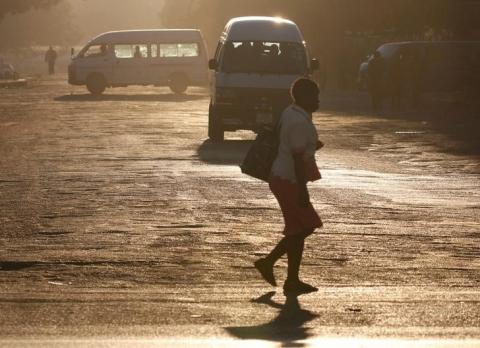 A woman crosses the street in front of minibus taxis in Harare, Zimbabwe, August 31, 2016. PHOTO BY REUTERS/Philimon Bulawayo