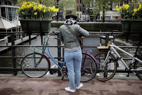 A woman parks her bike beneath boxes of daffodils on a bridge in Amsterdam, Netherlands, April 22, 2017. PHOTO BY REUTERS/Kevin Coombs