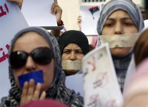 Libyan women with taped mouths take part in a silent march in support of the women who were raped during the war in Libya, in Tripoli