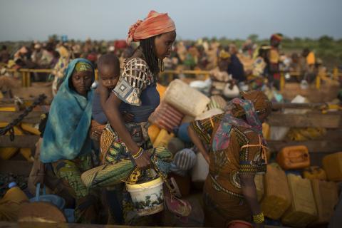 Women carry their belongings as they disembark from trucks carrying internally displaced muslims, after travelling in convoy escorted by the African Union operation in CAR (MISCA) on a four-day journey from the capital Bangui, at the transit IDP centre in the outskirts of the Central African Republic-Chad border town of Sido