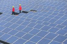 Workers walk past solar panels in Jimo, Shandong Province, China, April 21, 2016. PHOTO BY REUTERS/China Daily