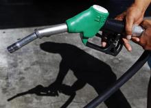 A customer uses a petrol nozzle to fill up his tank in a gas station