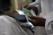 A man counts notes after receiving Sudanese currency at a central bank branch in Khartoum