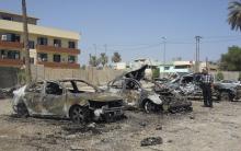 A man looks at damaged vehicles at the site of a car bomb attack in Baghdad's Kadhimiya district