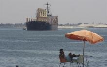 A man sits near a ship crossing the Suez Canal near Ismailia port city