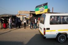 A taxi carrying the flag of the ruling African National Congress (ANC) party drives past locals queueing to cast their votes during the Local Government elections in Diepsloot township, north of Johannesburg, South Africa. PHOTO BY REUTERS/James Oatway