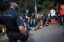 Police stand around a group of African migrants as Red Cross workers attend the injured after they crossed the border fence from Morocco to Spain's North African enclave of Ceuta, Spain, August 1, 2017. PHOTO BY REUTERS/Jesus Moron