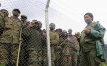 An army officer stands guards outside an enclosure filled with M23 rebel fighters who have surrendered to Uganda's government