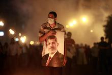 An injured supporter of deposed Egyptian President Mohamed Mursi carries a poster of Mursi