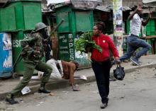 An anti riot policeman attempts to disperse people from the street as a woman carrying vegetables walks past in Mathare, in Nairobi, Kenya, August 9, 2017. PHOTO BY REUTERS/Thomas Mukoya