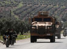 Turkish-backed Free Syrian army members ride on a motorbike near a Turkish military vehicle in Afrin, Syria, March 19, 2018. PHOTO BY REUTERS/Khalil Ashawi
