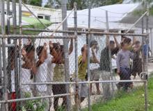 Asylum-seekers look through a fence at the Manus Island detention centre in Papua New Guinea, a March 21, 2014. PHOTO BY REUTERS/Eoin Blackwell