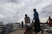 Women carry a bag of sorghum during food distribution in Minkaman, Lakes State, June 26, 2014. PHOTO BY REUTERS/Andreea Campeanu