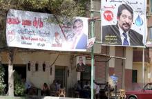 People sit at a coffee shop under election banners for parliamentary candidates in the Imbaba district of Giza, Egypt, October 13, 2015. PHOTO BY REUTERS/Mohamed Abd El Ghany