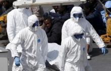 Armed Forces of Malta personnel in protective clothing carry the body of a dead immigrant off the Italian coastguard ship Bruno Gregoretti as surviving migrants watch in Senglea, in Valletta's Grand Harbour, April 20, 2015. PHOTO BY REUTERS/Darrin Zammit Lupi