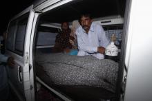 Mohammad Iqbal sits next to his wife Farzana's body, who was killed by family members, in an ambulance outside of a morgue in Lahore