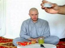U.S. Army Private Bowe Bergdahl watches as one of his captors display his identity tag to the camera at an unknown location in Afghanistan in this July 19, 2009 file still image taken from video