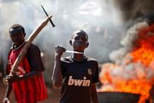 A boy gestures in front of a barricade on fire during a protest after French troops opened fire at protesters blocking a road in Bambari