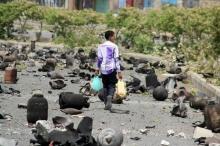 A boy walks on a street littered with cooking gas cylinders after a fire and explosions destroyed a nearby gas storage during clashes between fighters of the Popular Resistance Committees and Houthi fighters, in Yemen's southwestern city of Taiz, July 19, 2015. PHOTO BY REUTERS/Stringer