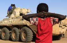 A boy looks on as a military convoy of government forces accompanying Special Prosecutor for Crimes in Darfur Yasir Ahmed Mohamed and his team arrives in Tabit village in North Darfur, November 20, 2014. PHOTO BY REUTERS/Mohamed Nureldin Abdallah