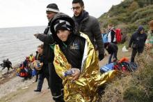 A migrant boy wrapped with a thermal blanket holds a pair of dry socks moments after refugees and migrants arrived on a raft on a beach on the the Greek island of Lesbos, January 29, 2016. PHOTO BY REUTERS/Darrin Zammit Lupi