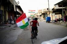 A boy rides a bicycle with the flag of Kurdistan in Tuz Khurmato, Iraq, September 24, 2017. PHOTO BY REUTERS/Thaier Al-Sudani