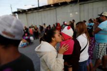 A member of a migrant caravan from Central America kisses a baby as they pray in preparation for an asylum request in the U.S., in Tijuana, Baja California state, Mexico, April 28, 2018. PHOTO BY REUTERS/Edgard Garrido