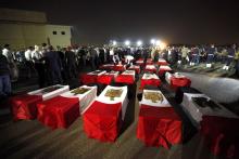 The caskets of 25 policemen killed in an ambush by Islamist militants near the north Sinai town of Rafah lie on the ground after arriving at Almaza military airport in Cairo