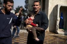 A man carries an injured child as another man gestures at a site hit by missiles fired by Syrian government forces on a busy marketplace in the Douma neighborhood of Damascus, Syria, October 30, 2015. PHOTO BY REUTERS/Bassam Khabieh