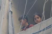 Children look out from a balcony at a site hit by airstrikes, in the rebel-held area of Aleppo's Bustan al-Qasr, Syria, April 29, 2016. PHOTO BY REUTERS/Abdalrhman Ismail