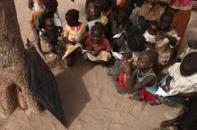 Refugee children copy notes from a chalkboard during an open-air English lesson under a tree at the Yida camp in South Sudan's Unity State