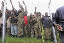 Congolese M23 rebel fighters gather inside an enclosure after surrendering to Uganda's government