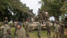 Congolese soldiers pose on a tank to celebrate their victory after taking over the headquarters of the M23 rebels at Rutshuru, north of Goma