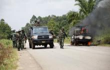 Congolese soldiers from the Armed Forces of the Democratic Republic of Congo (FARDC) stand next to their burning vehicle after an ambush near the village of Mavivi in North Kivu province