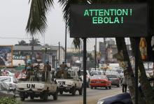 A U.N. convoy of soldiers passes a screen displaying a message on Ebola on a street in Abidjan