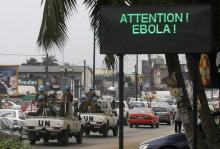 A U.N. convoy of soldiers passes a screen displaying a message on Ebola on a street in Abidjan, August 14, 2014. PHOTO BY REUTERS/Luc Gnago