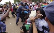 Mourners fall during a stampede as they run to queue before boarding buses to take them to the Union Buildings, where former South African President Nelson Mandela is lying in state, in Pretoria