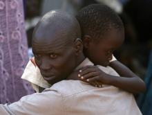 An internally displaced man holds his son inside a United Nations Missions in Sudan (UNMIS) compound in Juba