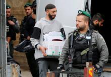 An undercover Israeli security officer carries a box containing documents seized from a Palestinian map office by Israeli security officers as they carry out an Israeli police order to close the office, in the Arab East Jerusalem neighbourhood of Beit Hanina, March 14, 2017. PHOTO BY REUTERS/Ammar Awad