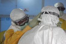 Dr. Joel Montgomery, team leader for the U.S. Centers for Disease Control and Prevention Ebola Response Team in Liberia, is dressed in his personal protective equipment while adjusting a colleague's PPE before entering the Ebola treatment unit in Monrovia, Liberia's capital city