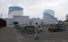 An employee of Kyushu Electric Power Co walks in front of reactor buildings at the company's Sendai nuclear power plant in Satsumasendai, Kagoshima prefecture, April 3, 2014. PHOTO BY REUTERS/Mari Saito